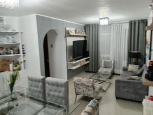sala de estar con sofá, TV y sillas en Comodidad en tu viaje, en Chiclayo