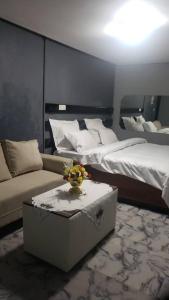 a room with two beds and a couch and a table at Sunrise Center Bonapriso - 107 in Douala