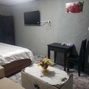 Cette chambre comprend un lit et une table avec un bureau. dans l'établissement Sunrise Center Bonapriso - 107, à Douala