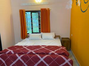 a bedroom with a bed and a window with orange curtains at Heavenly Stay in Thekkady