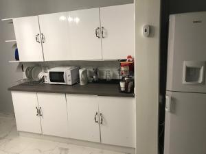 a kitchen with white cabinets and a microwave at Rose Cottage in Tipton