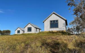 two white houses on top of a grassy hill at Áskot Cottages in Hella