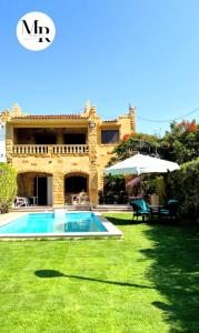 uma casa com piscina e guarda-sol em Villa Marina (5) 2nd Row Of The Sea em El Alamein
