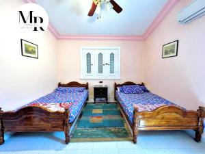 a bedroom with two beds and a rug at Villa Marina (5) 2nd Row Of The Sea in El Alamein
