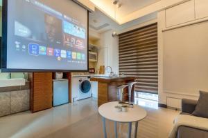 a living room with a flat screen tv and a table at 1B1b Cinema, Kitchen, Bathtub, Desk, 1.5min to MRT • 1房1衛 家庭戲院、廚房、浴缸、書桌，1.5分到市府捷運 in Taipei