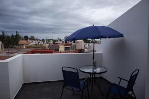 uma mesa com cadeiras e um guarda-sol azul numa varanda em Casa en puebla em El Gallinero
