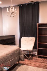 a bedroom with a bed and a chair and a chandelier at Parkton Place An Outdoor Venue in Hope Mills
