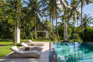 a pool with lounge chairs next to a house at Anima Retreat Bali in Krambitan