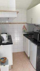 Elle comprend une petite cuisine avec des placards blancs et un évier. dans l'établissement Central Lisbon Sao Jorge 2 bedroom private apartment, à Lisbonne