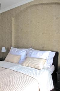 un letto con lenzuola e cuscini bianchi accanto a un muro di Moravia Boutique Apartments a Karlovy Vary