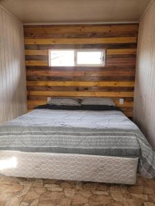 a bedroom with a bed in a wooden wall at cabañaNavidad in El Culenar