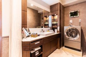uma casa de banho com um lavatório e uma máquina de lavar roupa em Hotel Pasela Living em Tóquio