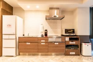 a kitchen with a white refrigerator and a microwave at Hotel Pasela Living in Tokyo