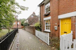 a yellow door on the side of a brick building at Quaint 2-Bed Cottage in the heart of Ashford in Ashford