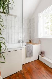 ein weißes Badezimmer mit einer Badewanne und einem Waschbecken in der Unterkunft Quaint 2-Bed Cottage in the heart of Ashford in Ashford