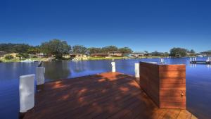 a wooden dock with a table on the water at Love the Let! in Sussex Inlet