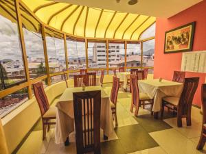 restauracja ze stołami i krzesłami oraz dużymi oknami w obiekcie Gran Kunturwasi Hotel Senior w mieście Cajamarca