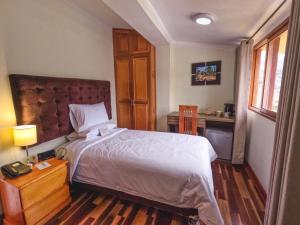a bedroom with a large bed and a desk at Gran Kunturwasi Hotel Senior in Cajamarca