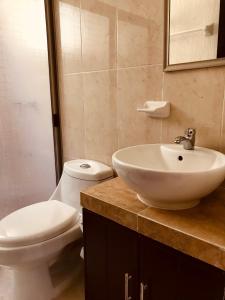 une salle de bain avec un lavabo blanc et des toilettes dans l'établissement Bonita Casa Vacacional. Punto medio entre ciudad y playa, à Mérida 18 autres photos