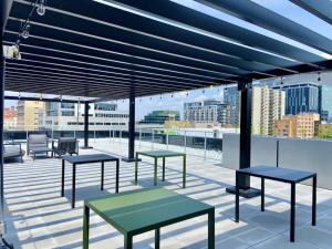 eine Terrasse mit Bänken und Tischen auf dem Dach in der Unterkunft Appartement condo avec terrasse privée dans le Quartier des Spectacles in Montreal