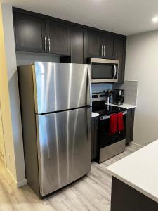 a stainless steel refrigerator in a kitchen with black cabinets at The Waterfront cozy 1 bd suite in Rockland Park, Tuscany NW in Calgary