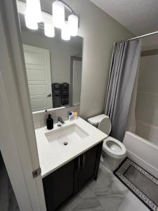 a bathroom with a sink and a toilet and a mirror at The Waterfront cozy 1 bd suite in Rockland Park, Tuscany NW in Calgary