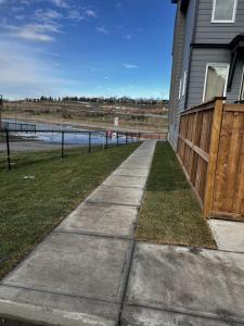 einen Bürgersteig neben einem Haus mit einem Zaun in der Unterkunft The Waterfront cozy 1 bd suite in Rockland Park, Tuscany NW in Calgary