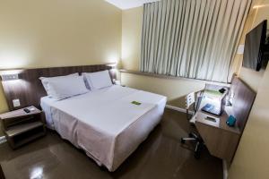 クイアバにあるSlim Cuiabá Aeroportoのベッドとテレビがあるホテルの部屋