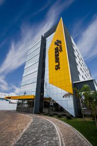 a building with a yellow sign on the side of it at Slim Cuiabá Aeroporto by Slaviero Hotéis in Várzea Grande