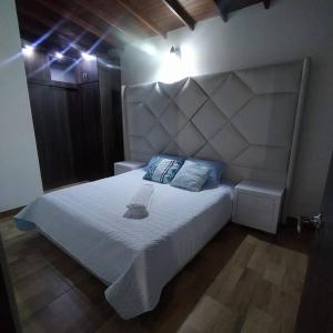 a bedroom with a white bed with a large headboard at Hermoso apartamento en Medellín in Medellín
