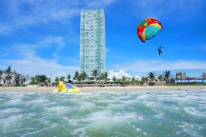 una persona está volando una cometa en la playa en Fusion Suites Da Nang - Daily Reflexology Inclusive, en Da Nang