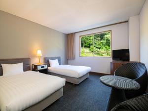 a hotel room with two beds and a window at Kirishima Kokusai Hotel in Kirishima