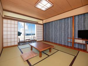 a japanese room with a table and a television at Kirishima Kokusai Hotel in Kirishima