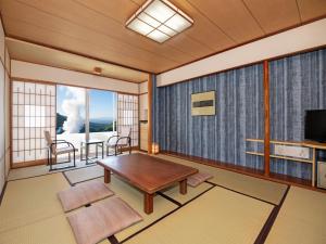 a living room with a table and a large window at Kirishima Kokusai Hotel in Kirishima