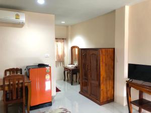 ein Wohnzimmer mit einem orangen Kühlschrank und einem Tisch in der Unterkunft Ratchaphruek Resort in Lop Buri