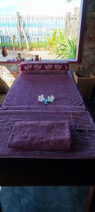 a purple bed with purple sheets and flowers on it at Thoduwawa Beach Villa in Paiyagala South