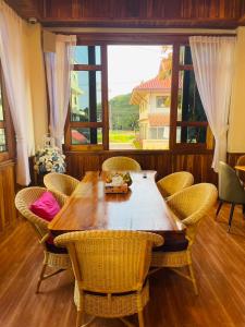 a dining room table with chairs and a large window at Kum-Chan House Hotel (เฮือนก่ำจันทร์) in Nan