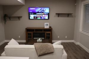 a living room with a white couch and a flat screen tv at Golden Ears Nature's Delight in Maple Ridge District Municipality