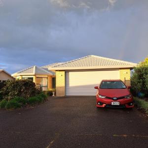 ein rotes Auto, das vor einem Haus parkt in der Unterkunft Hosts on the Coast - Rosberg Retreat in Mount Maunganui