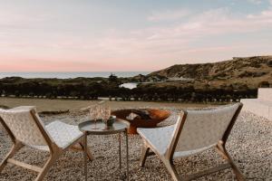 a table and two chairs on a gravel patio with the ocean at Middle River Vista Beach House in Stokes Bay