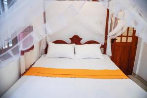 1 dormitorio con 1 cama con sábanas blancas y naranjas en Vision Home, en Ambalangoda