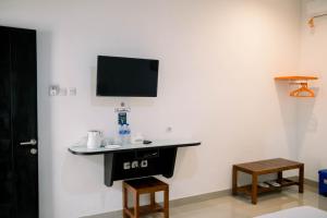 Zimmer mit einem Schreibtisch und einem TV an der Wand in der Unterkunft Morika Inn in Waikabubak