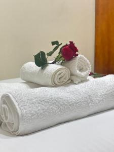 - une pile de serviettes avec deux roses au-dessus dans l'établissement The Mbuya Residence, à Kampala