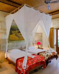 two beds in a room with a canopy bed at Mahagiri Resort & Restaurant in Menanga