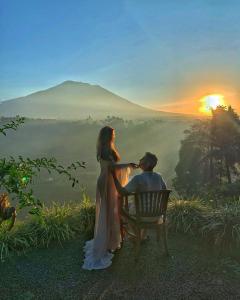 un homme et une femme assis sur un banc et regardant le coucher du soleil dans l'établissement Mahagiri Resort & Restaurant, à Menanga