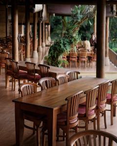 a row of wooden tables and chairs in a restaurant at Mahagiri Resort & Restaurant in Menanga