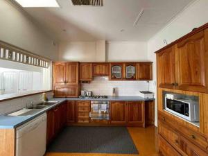 a large kitchen with wooden cabinets and a sink at Group house with views of the salt pool and spa in Mitcham