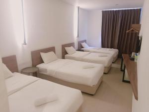 T Hotel Anggerik في ألور سيتار: غرفة فندقية بثلاث اسرة واريكة