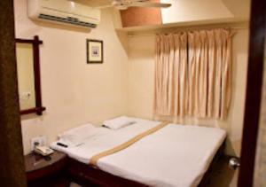 um quarto com uma cama branca e uma janela em Hotel Regency Maharashtra em Amravati