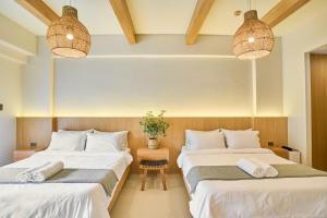 two beds in a room with two pendant lights at Yugen Suites 208 at Pico De Loro in Nasugbu